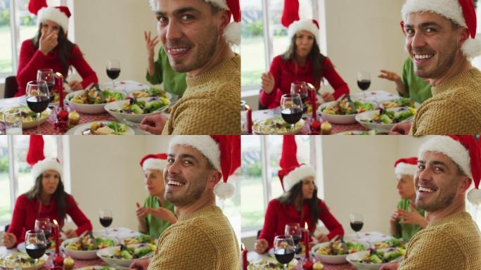 快乐的白人男子戴着圣诞帽看着相机在圣诞大餐