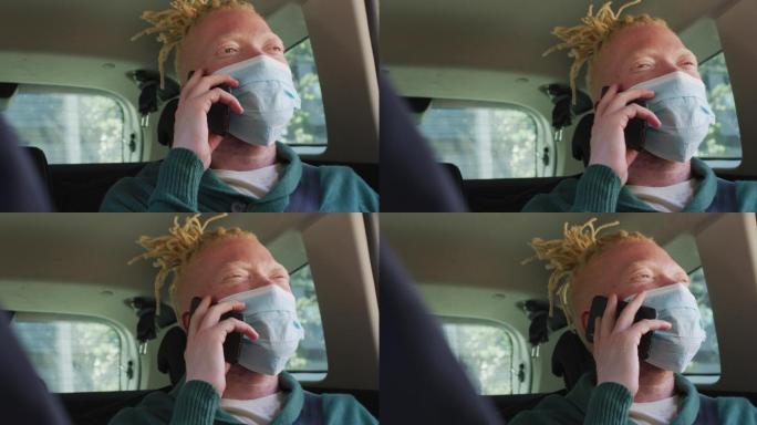 快乐的白化非裔美国人戴着口罩坐在车里用智能手机聊天