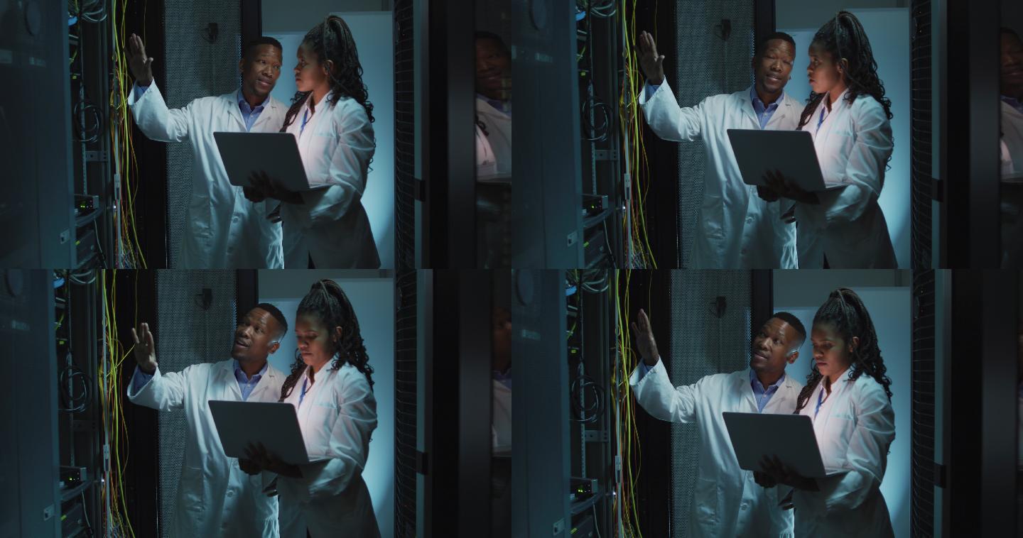 非裔美国计算机技术人员使用笔记本电脑在业务服务器室工作
