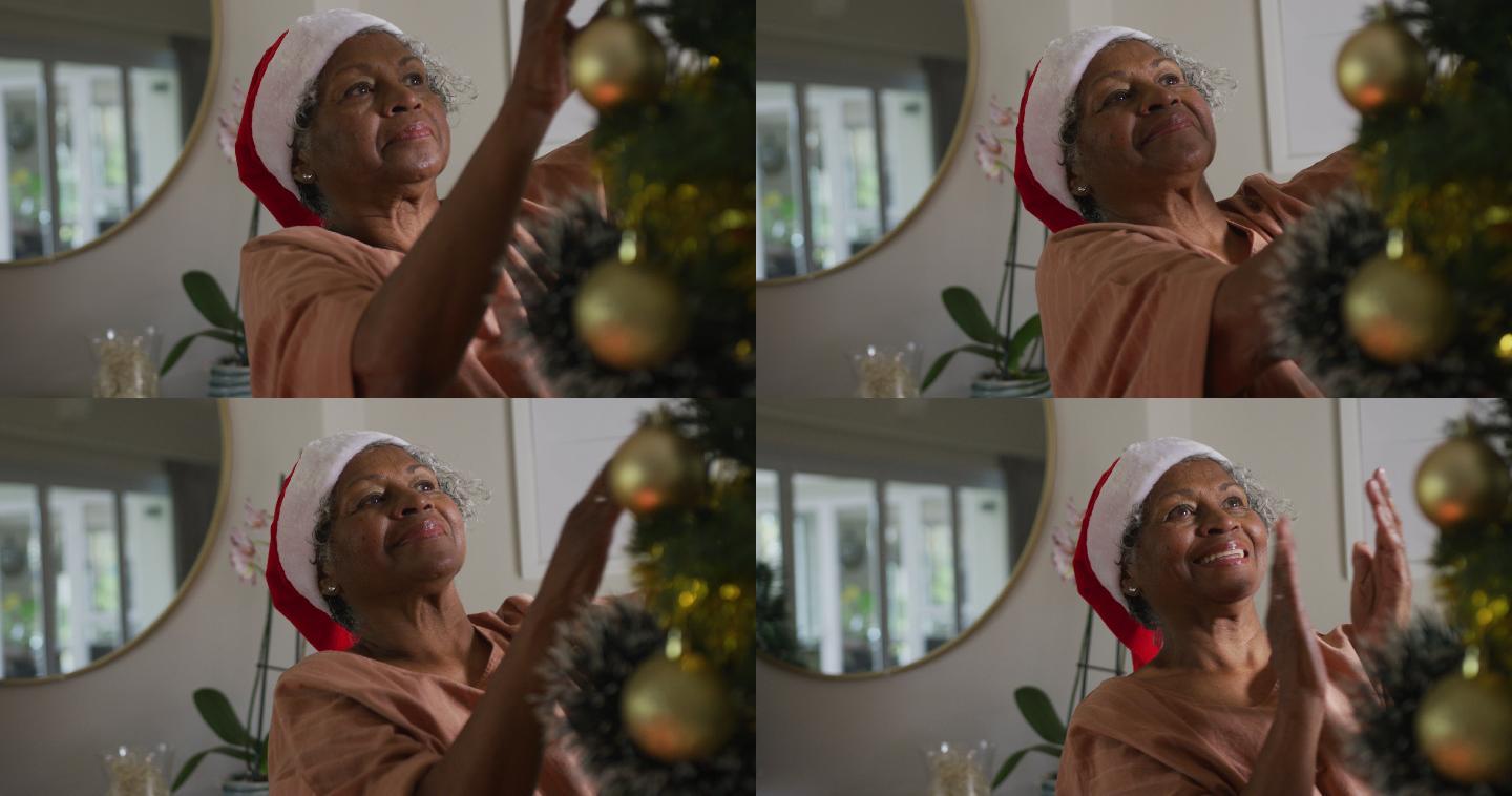 快乐的非裔美国老太太戴着圣诞帽装饰圣诞树