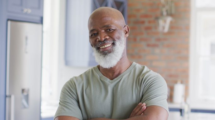 非裔美国老人的肖像与双臂交叉微笑在家里