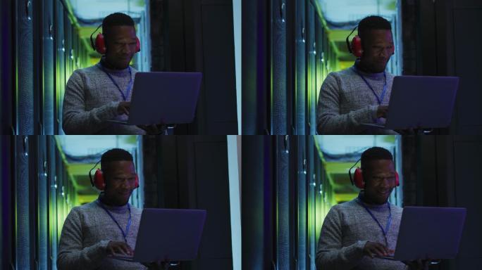 非裔美国男性电脑技术人员使用笔记本电脑在企业服务器室工作