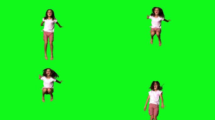 快乐女孩在绿色屏幕上的慢动作跳跃