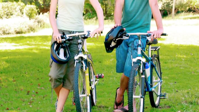 一对年轻夫妇骑着自行车站在公园里