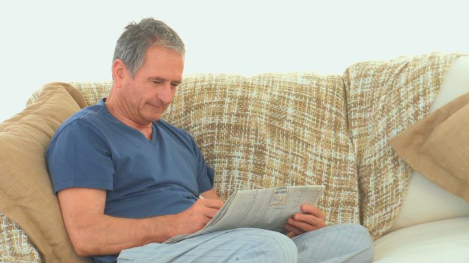 退休男子在沙发上玩填字游戏