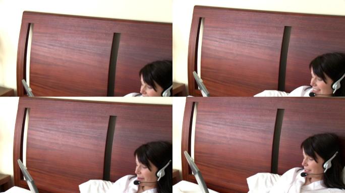 女人躺在床上戴着耳机看电脑特写