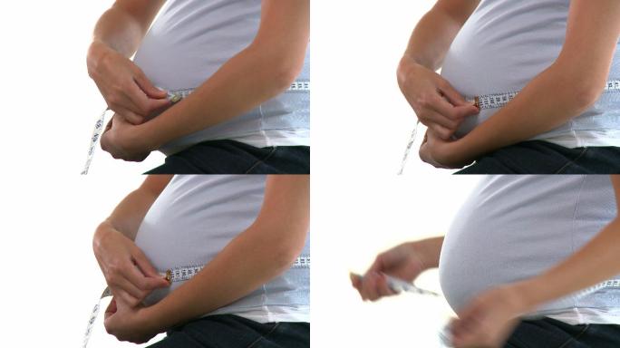 一个孕妇在测量她的腰特写