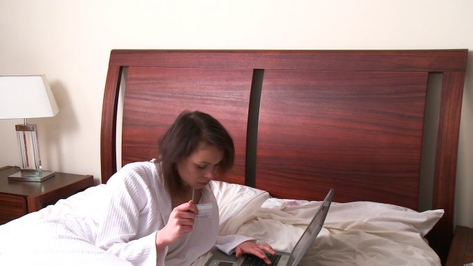女人坐在床上在网上购物特写