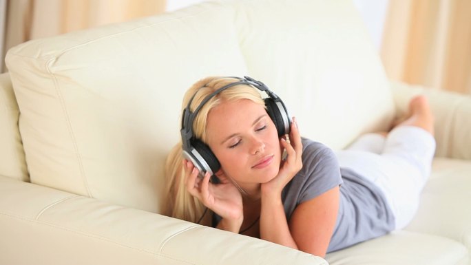 一个女人躺在沙发上听音乐特写