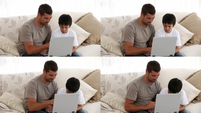 父亲和儿子在沙发上看电脑特学