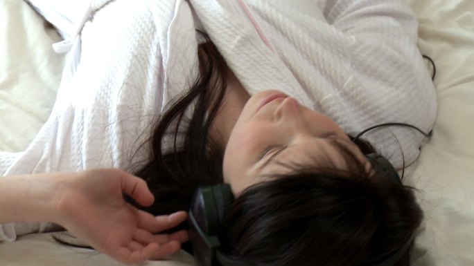 女人躺在床上听音乐特写