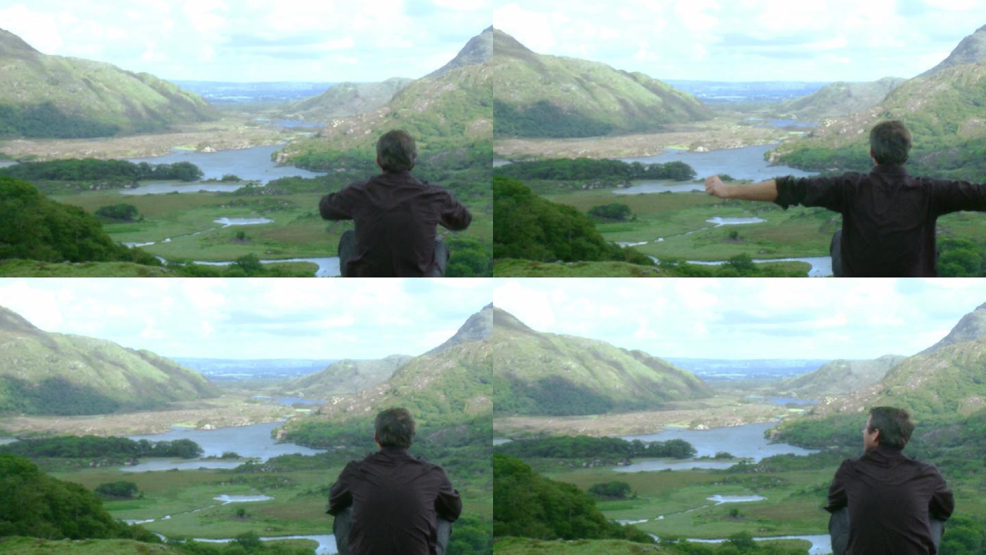男子坐在山顶上看风景特写