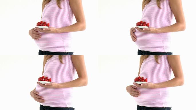 一个孕妇拿着碗草莓特写