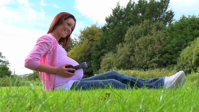 一位孕妇正坐在草坪上特写