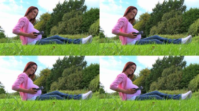一位孕妇正坐在草坪上特写