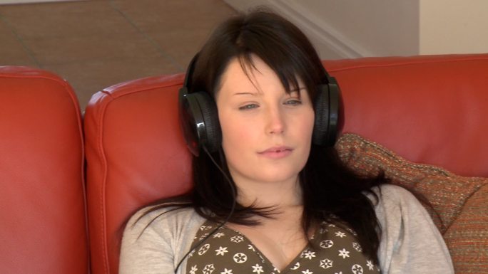 女人坐在沙发上听音乐特写