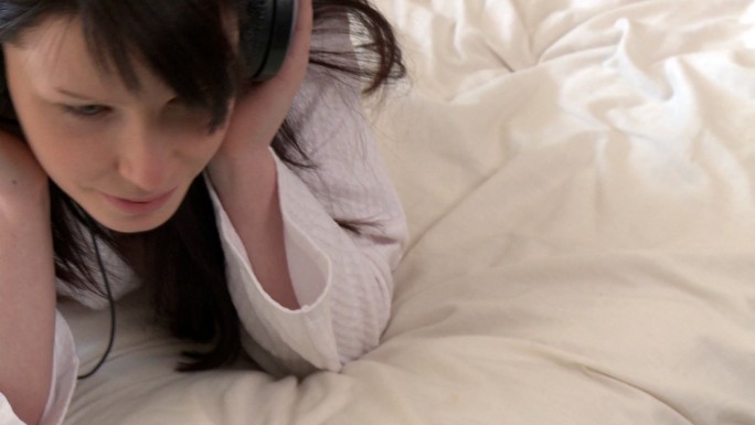 女人趴在床上听音乐特写