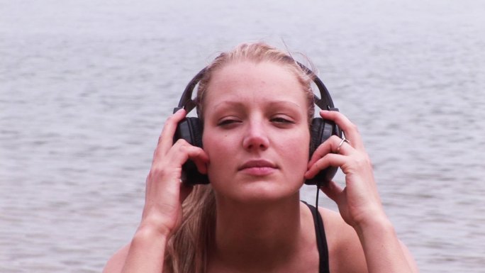 一个女人在海滩上听音乐特写
