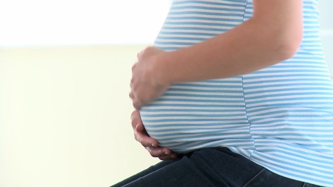一个孕妇在摸肚子特写