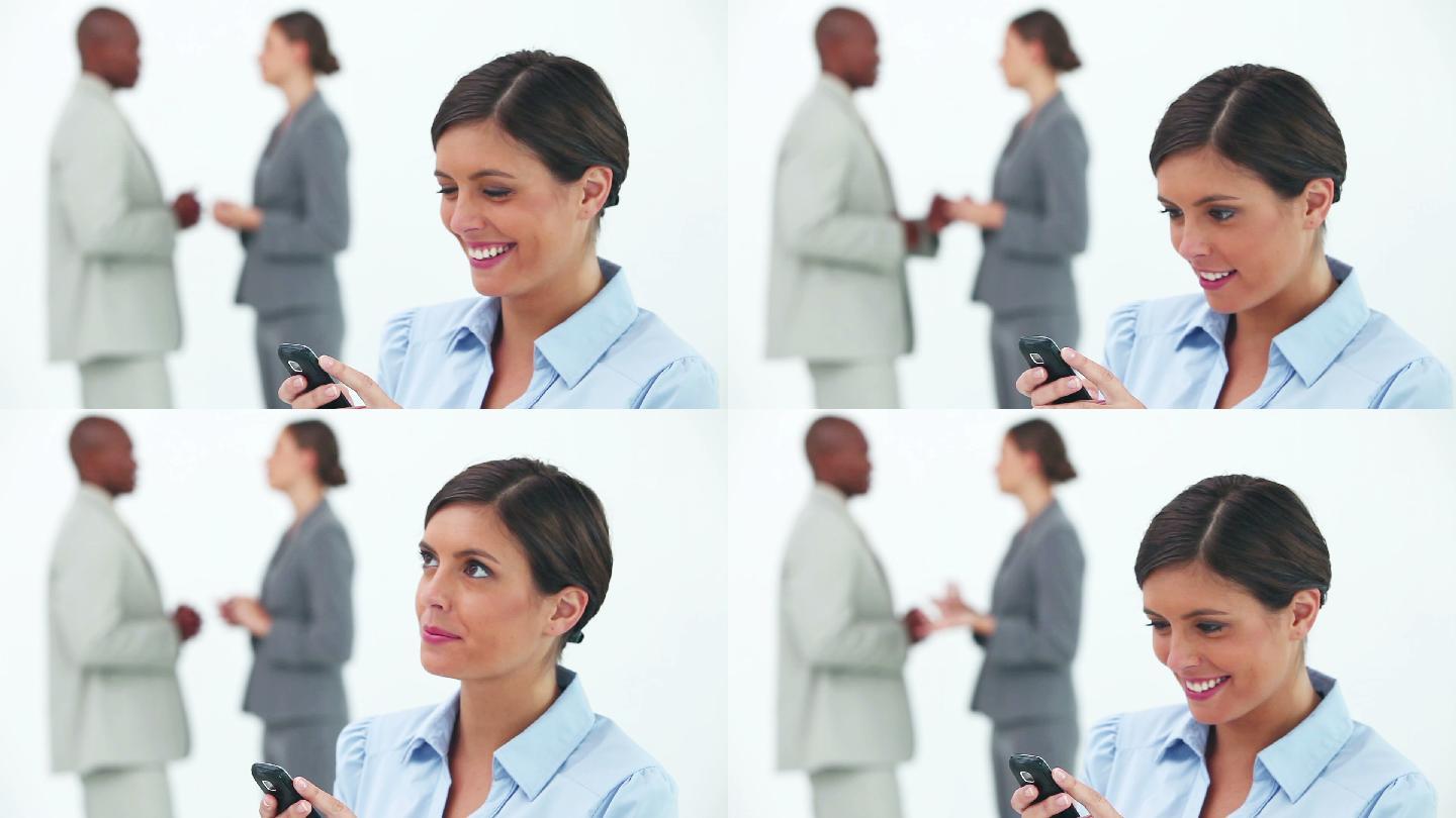 一个外国女人笑着看手机，两位同事在身后