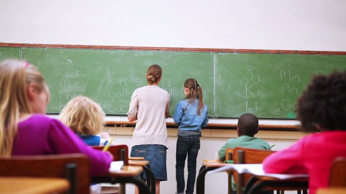 一个学生在教室的黑板上写字的后视图