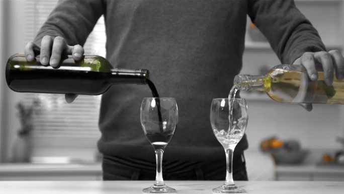 在慢镜头中，男子将红葡萄酒和白葡萄酒倒入两杯