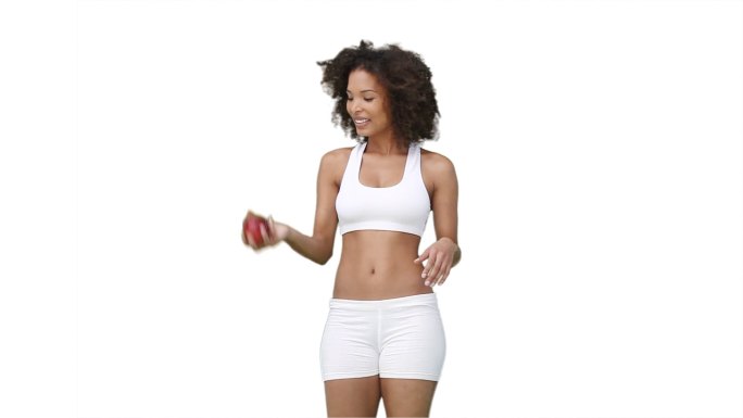 穿着训练服的女人在白色的背景下向上扔一个苹果