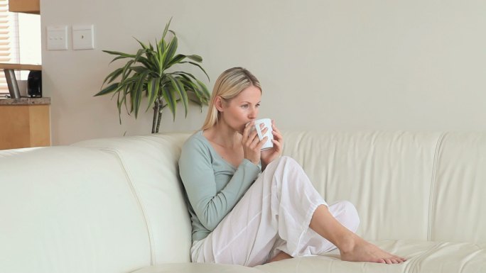 一个女人坐在客厅的沙发上喝咖啡