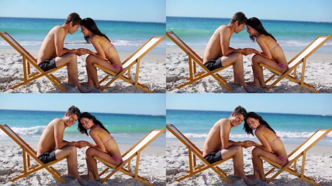 一对夫妇坐在沙滩上的躺椅上