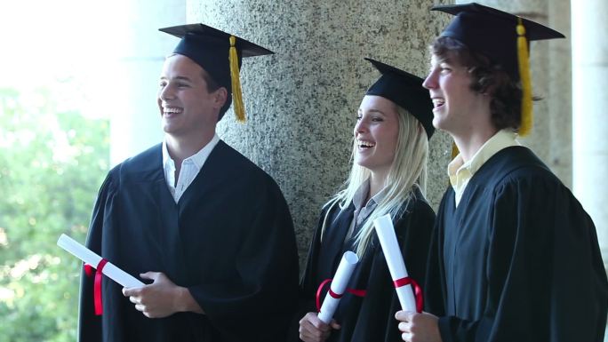 三个毕业生站在外面一起笑