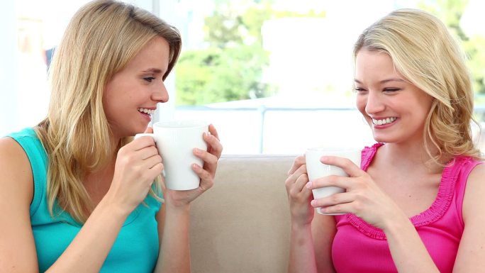 两个金发女人坐在沙发上喝咖啡