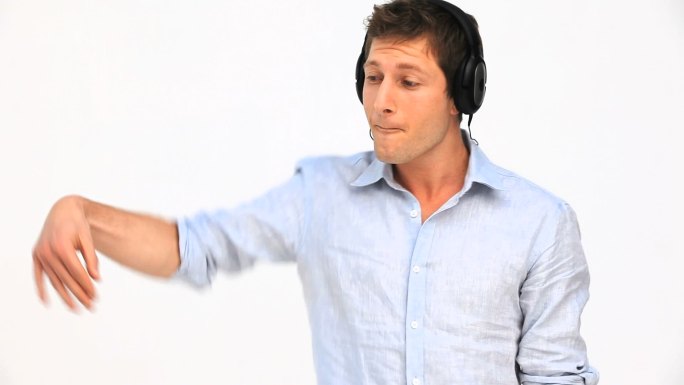 一个随意的男人带着耳机在白色的背景下听音乐