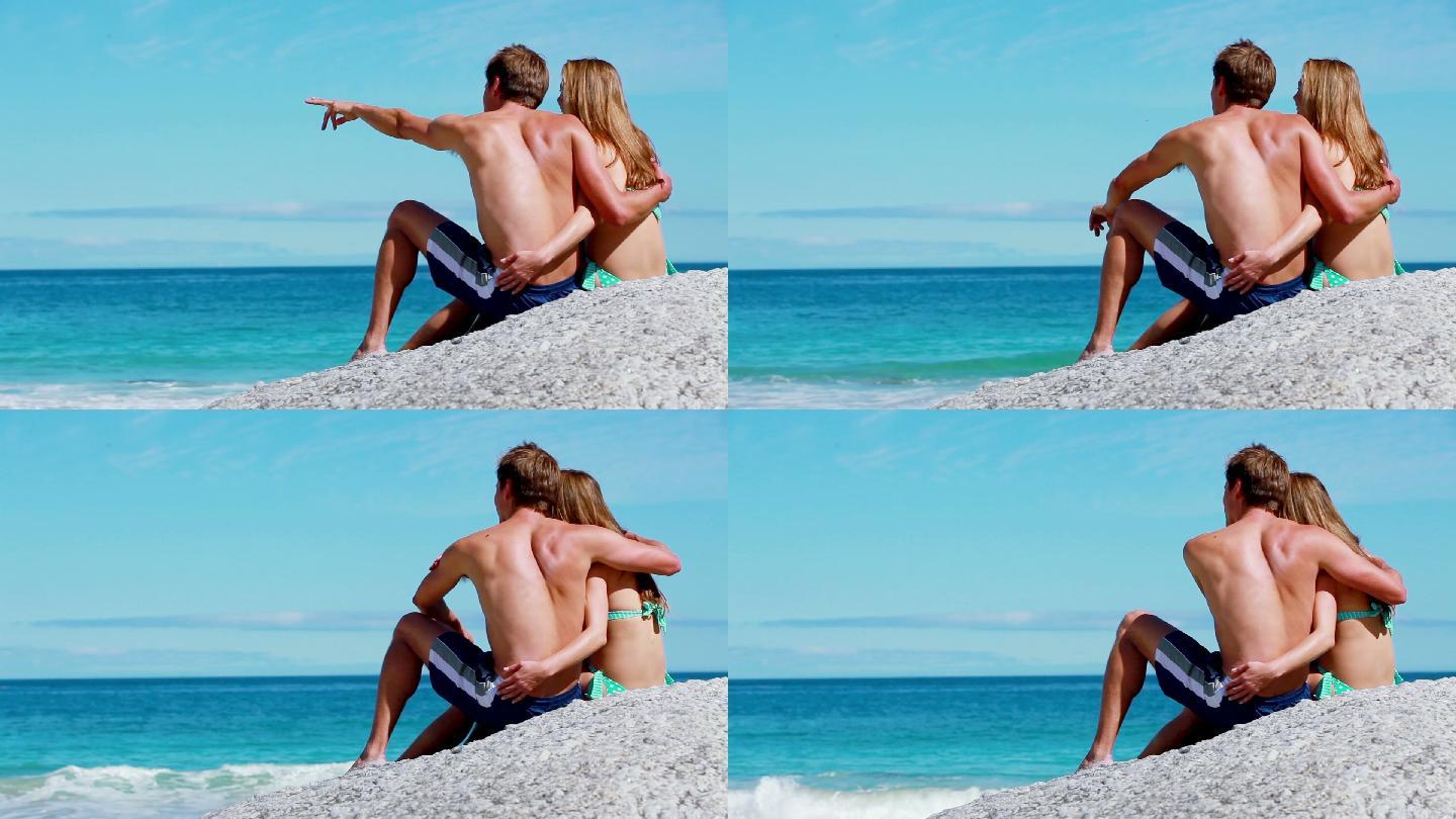 一对情侣坐在沙滩上拥抱在一起