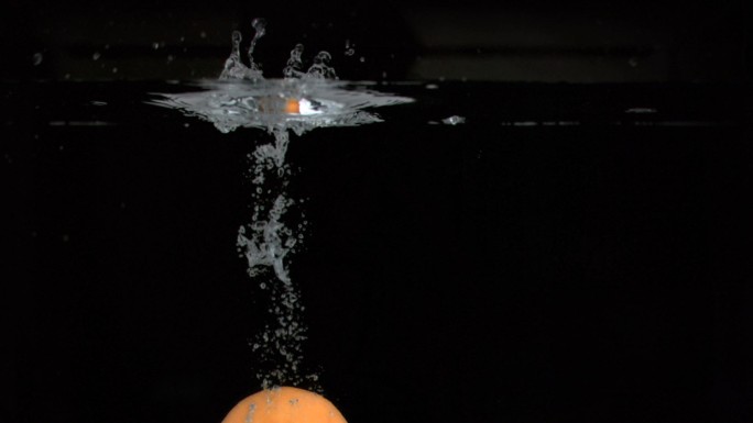橙子落入水中慢镜头，在黑色背景下