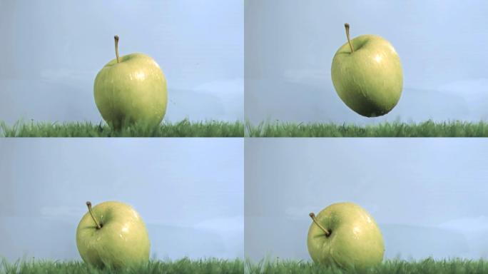 绿苹果在蓝色背景下以超慢的动作落在草地上