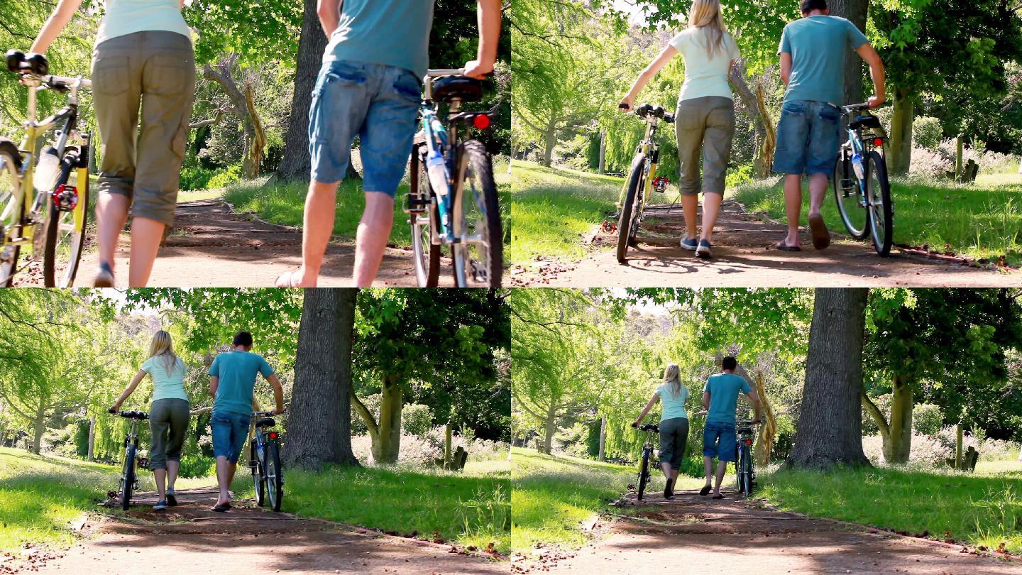 一个骑着自行车的男人和他的女朋友在公园里一瘸一拐的