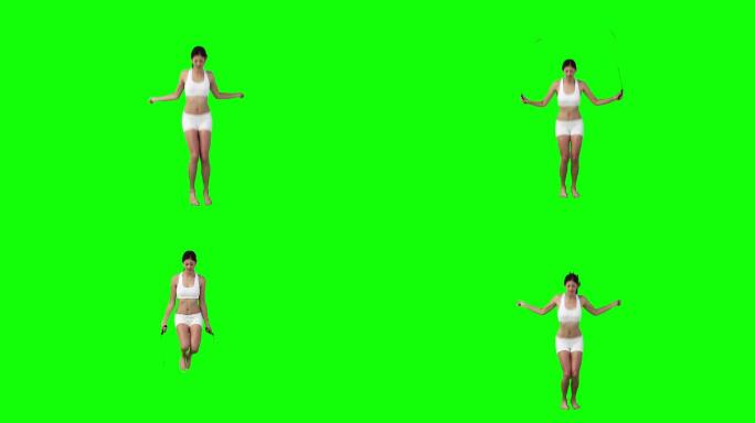 一个亚洲女性跳绳，在绿色背景下