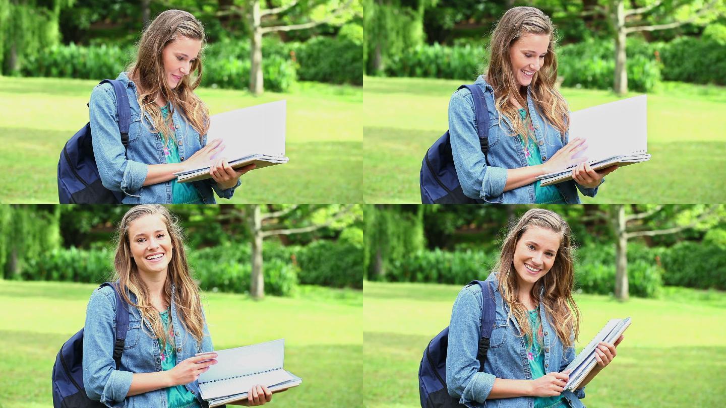 微笑的年轻女子打开她的笔记本在一个公园