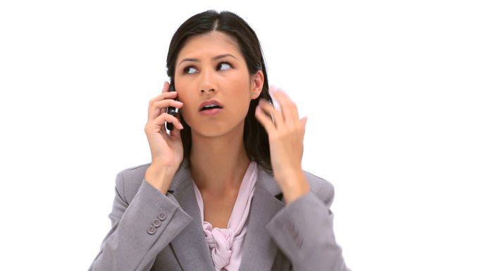 一个亚洲女性不高兴的打着电话在白色背景下