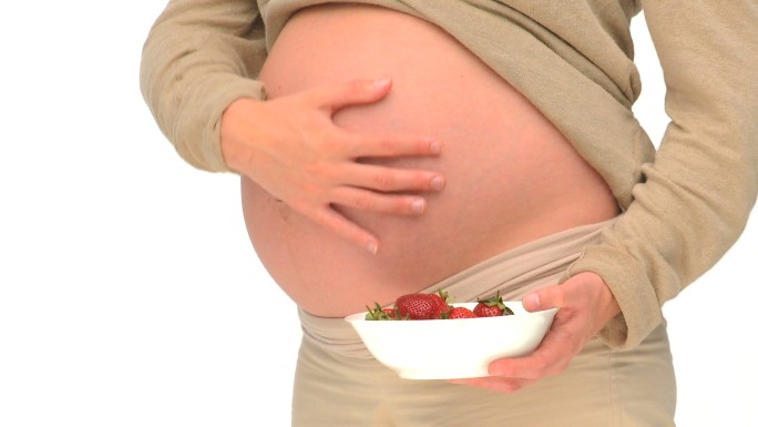 一个孕妇拿着一碗草莓特写镜头