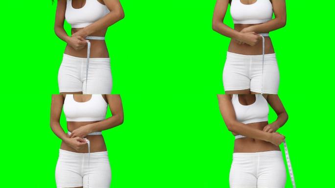 一个女性测量腰围特写镜头，在绿色背景下