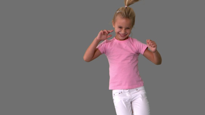 快乐的小女孩跳跃在灰色背景的慢镜头