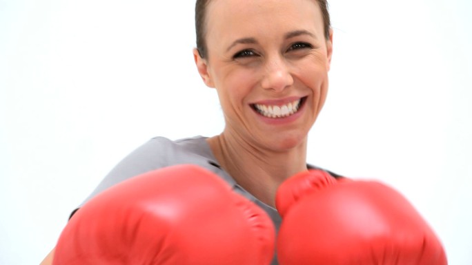 一个微笑的女人在一个白色的背景下拳击