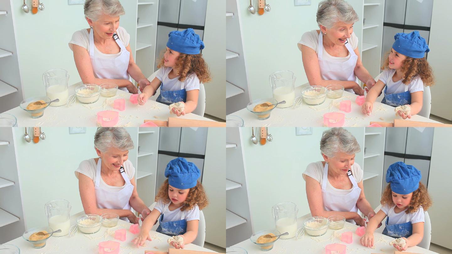 可爱的卷发女孩和她的奶奶在厨房烘焙