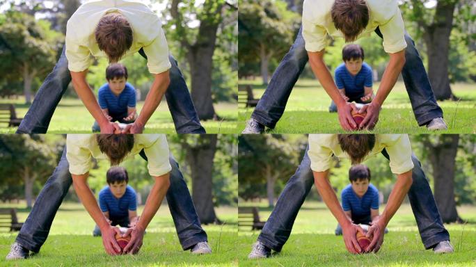 微笑的男人和他的儿子在乡下玩橄榄球