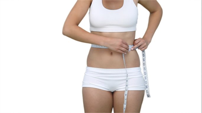 一个女人的近距离使用测量磁带在她的腰部对白色的背景