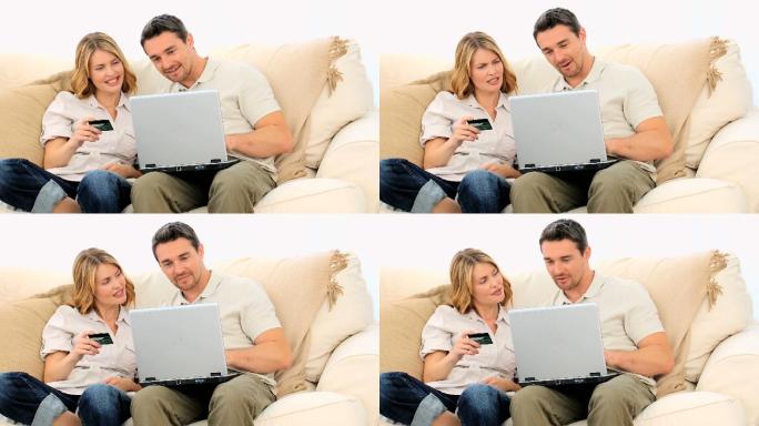 一对年轻漂亮的夫妇在客厅里用信用卡上网