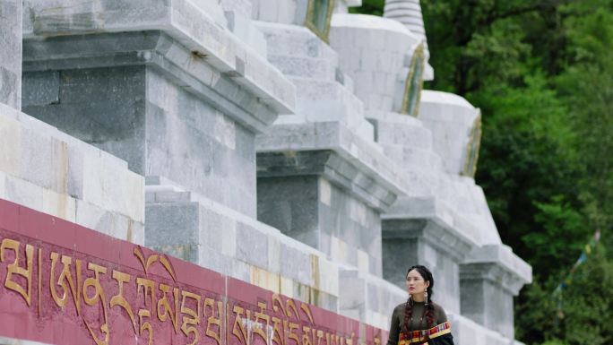 藏族女子在佛塔下行走祈愿