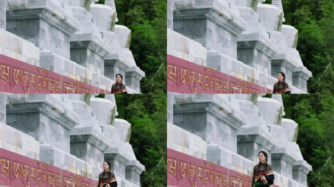 藏族女子在佛塔下行走祈愿