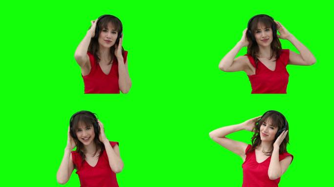 一名女子在绿色背景下戴着耳机跳舞